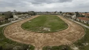Aerial view of horse racing track with sandy surface showing maintenance issues and empty grandstands